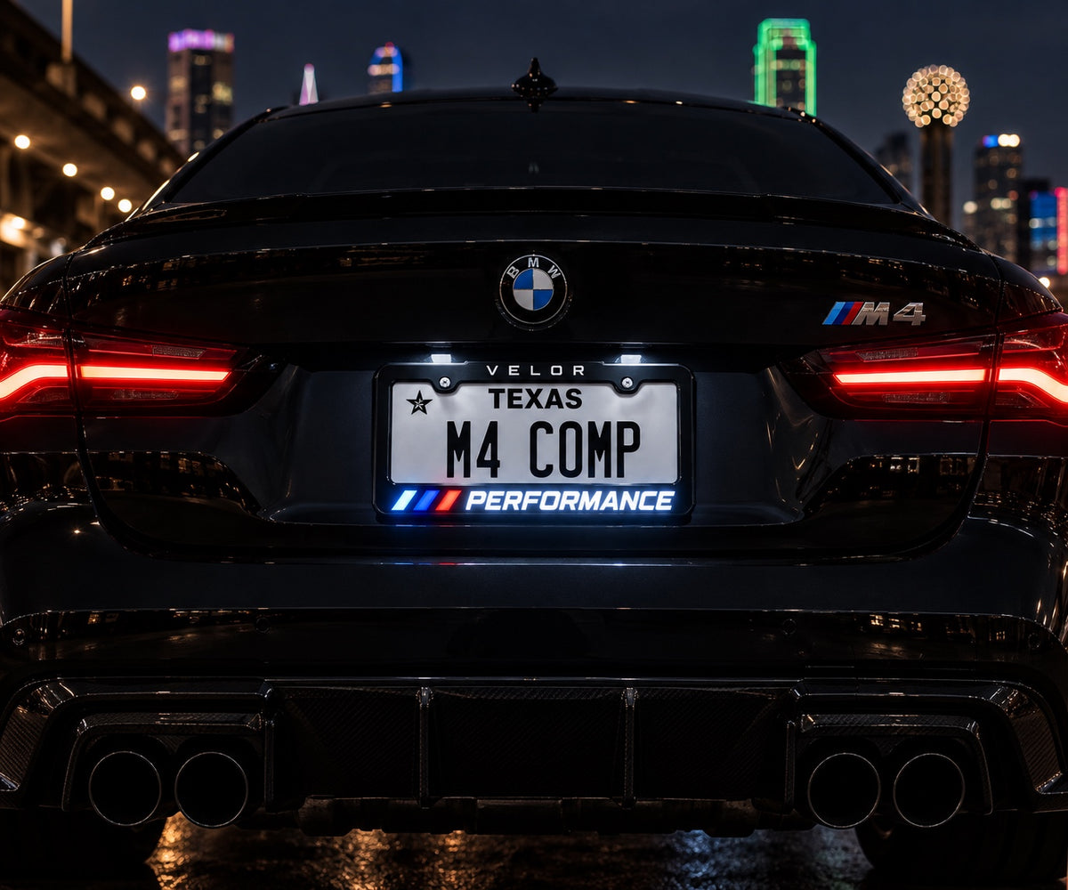Velor Works illuminated PERFORMANCE license plate frame installed on a black performance coupe at night