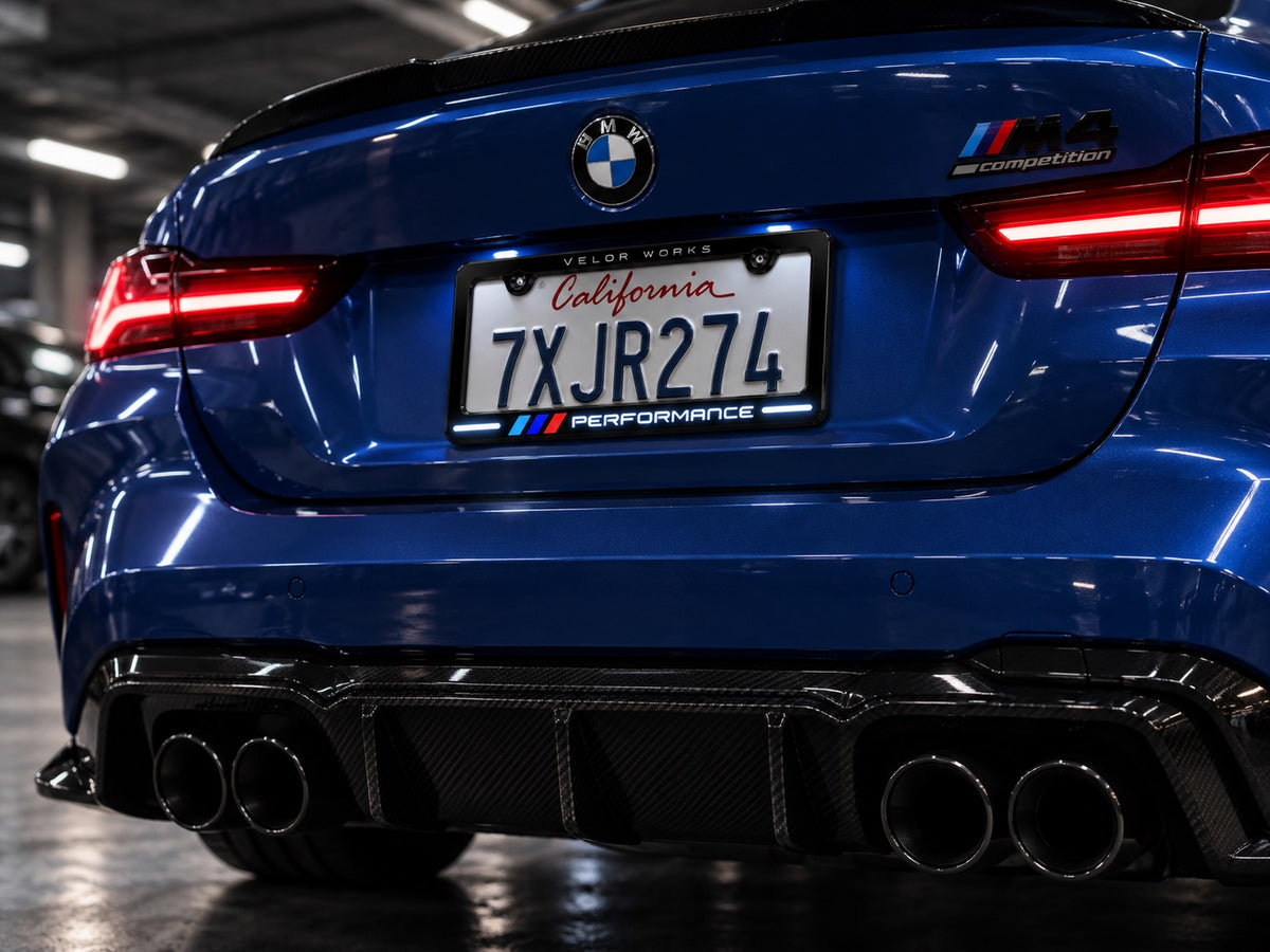 Velor Works Design B illuminated PERFORMANCE license plate frame on blue BMW M5 in garage