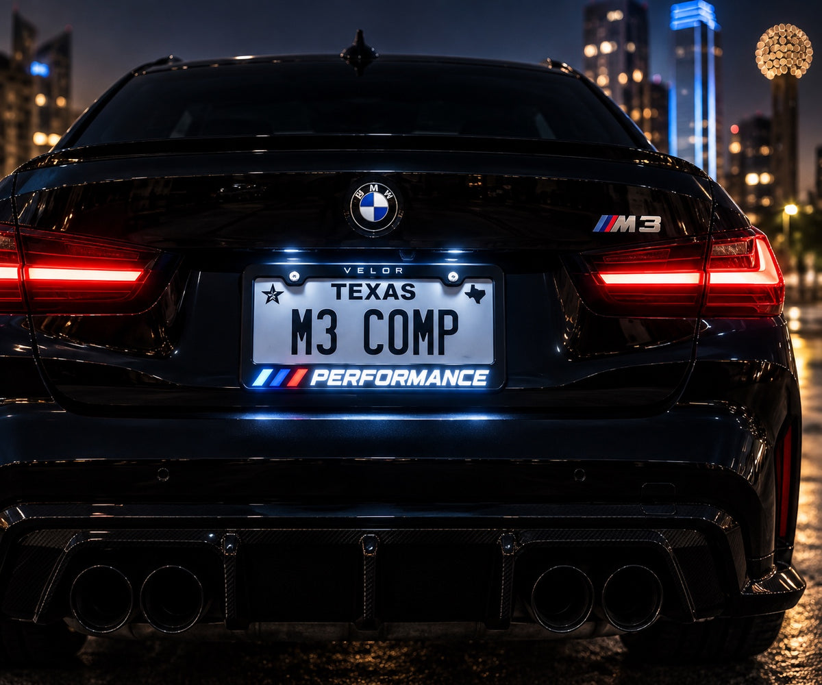 Velor Works illuminated PERFORMANCE license plate frame installed on a black performance sedan at night