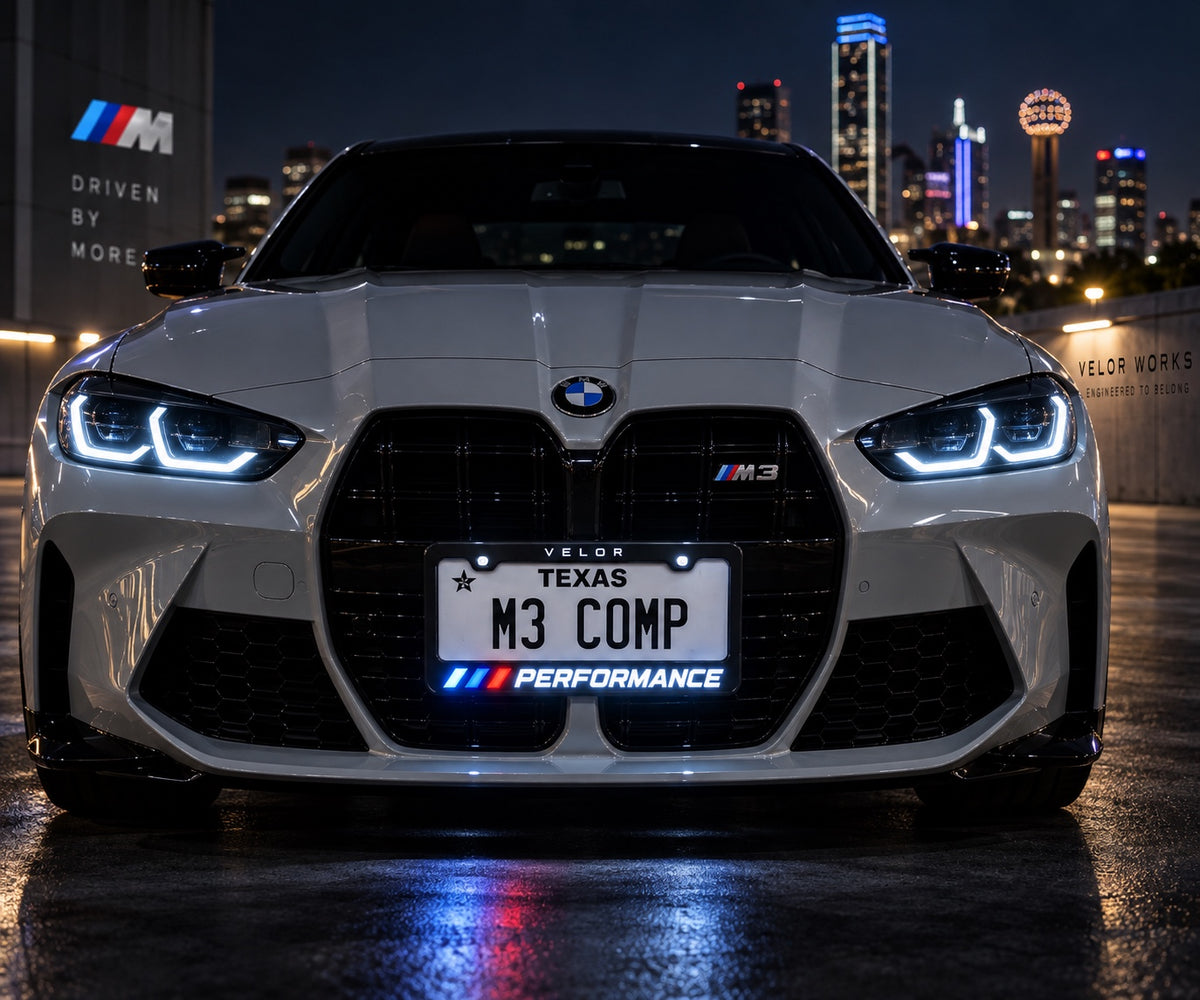 Velor Works illuminated PERFORMANCE license plate frame installed on a white performance sedan at night